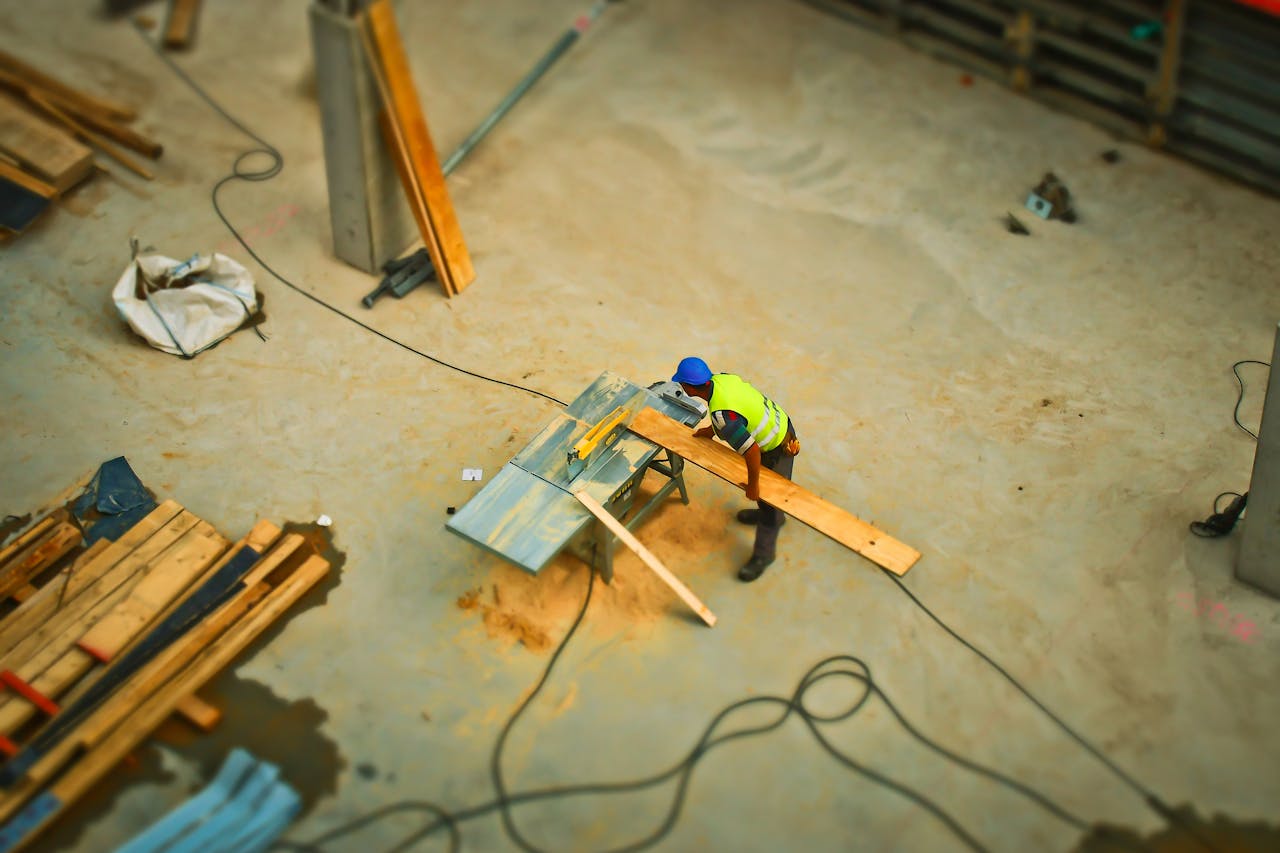 services-02 Overhead view of a construction worker using a saw to cut wood at a construction site.