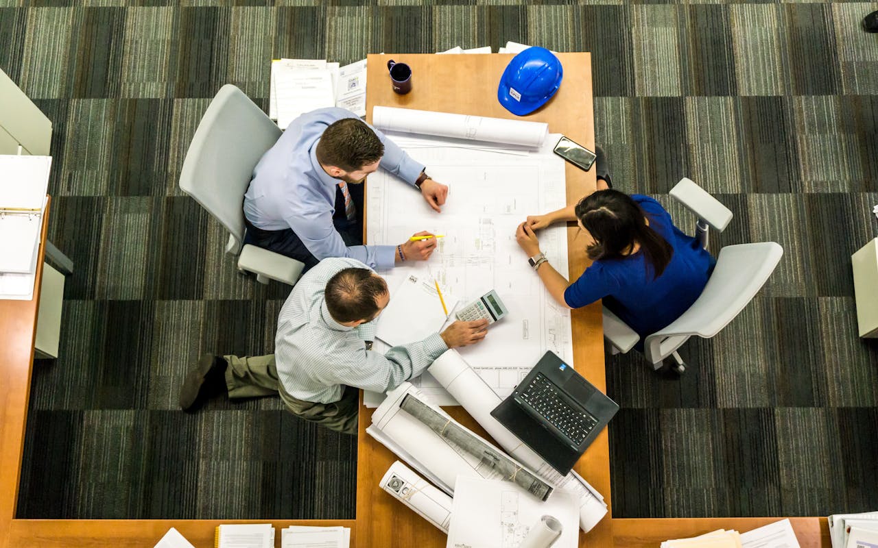 services-01 Top view of a team working on construction plans in an office setting.