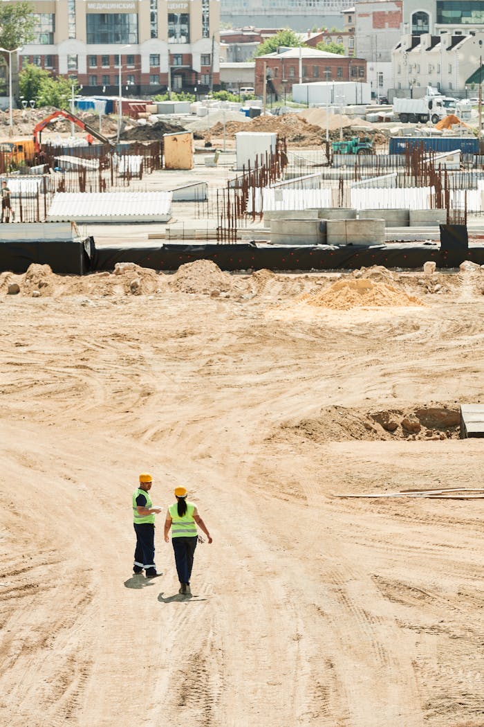 services-03 Overhead drone shot of a construction site with two workers in safety gear.