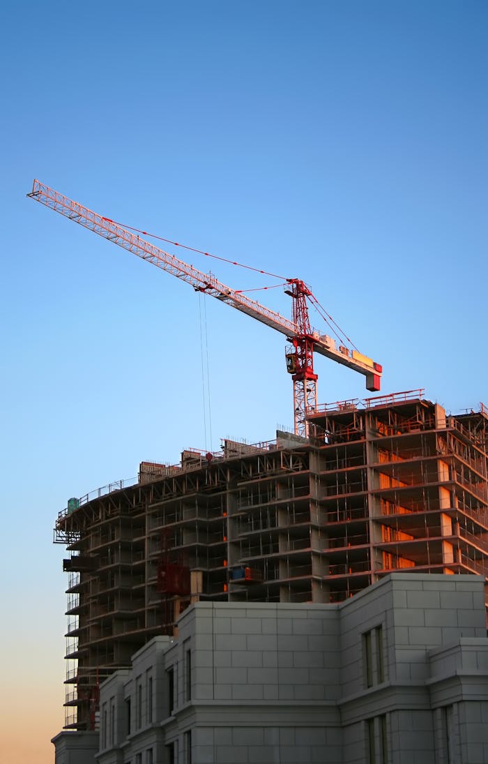 why-choose-us Tower crane on a high-rise building under construction at sunset, showcasing modern urban development.